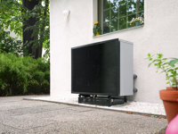 Kompakte Daikin Wärmepumpe im Garten vor einem Wohnhaus