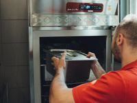 Mitarbeiter stellt Tablett in Gastronomie-Kühlgerät