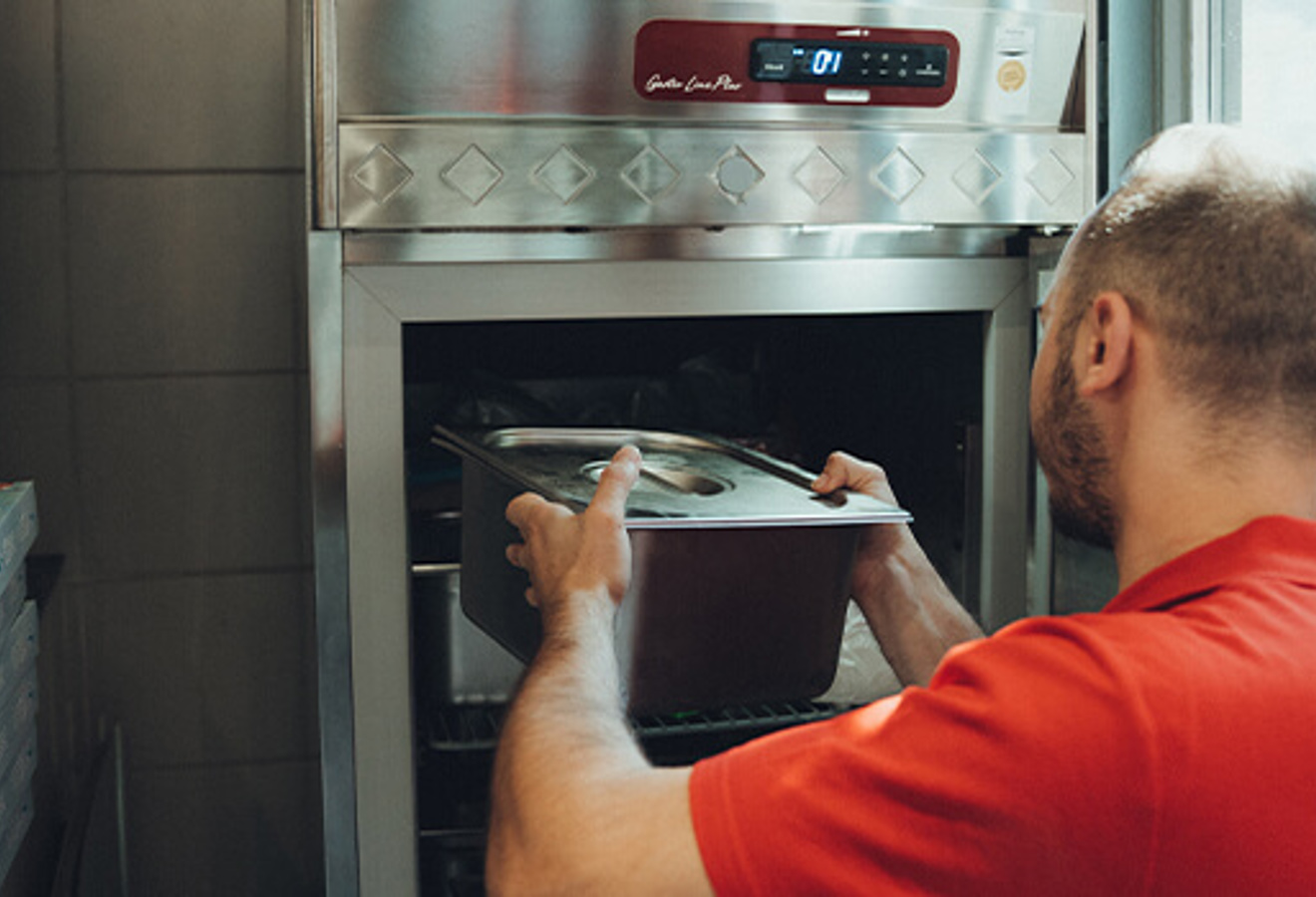 Mitarbeiter stellt Tablett in Gastronomie-Kühlgerät